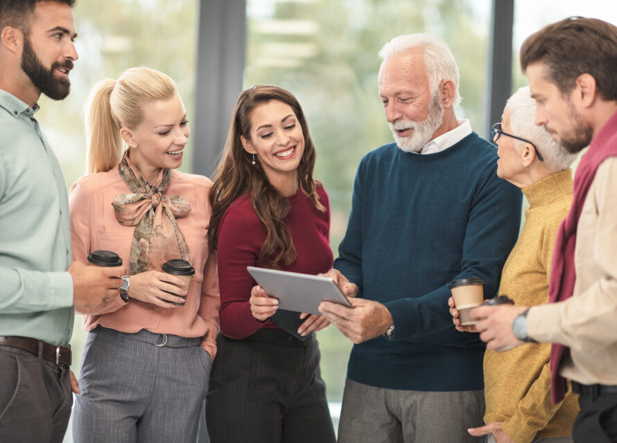 A small group of business people connecting warmly over coffee and a tablet — meaningful networking on purpose